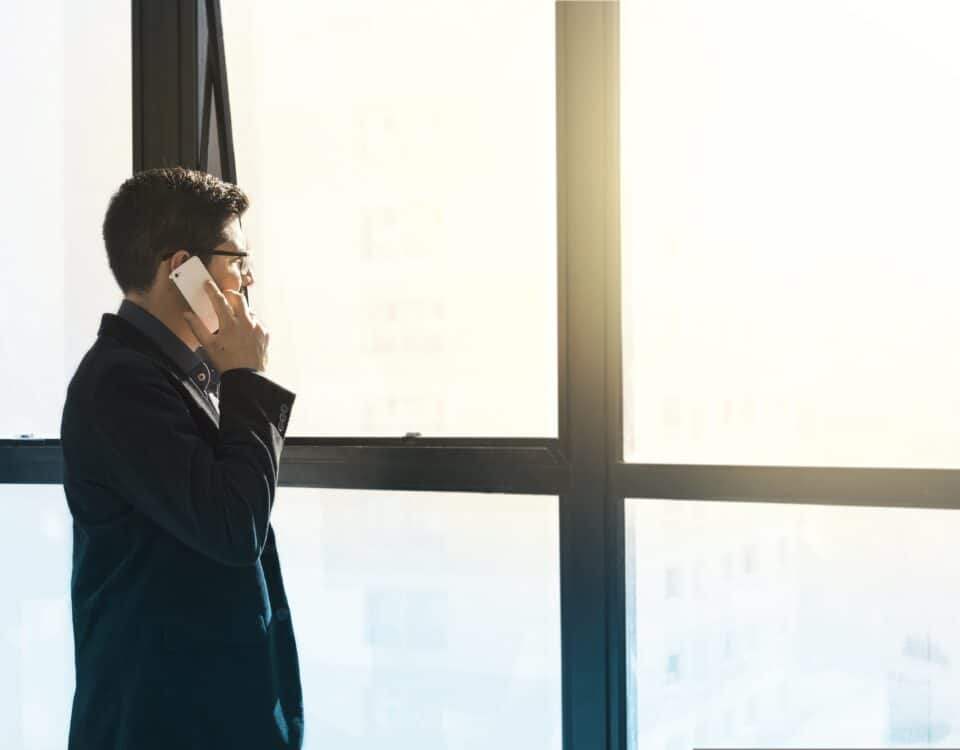 Mann am Fenster mit einem Smartphone